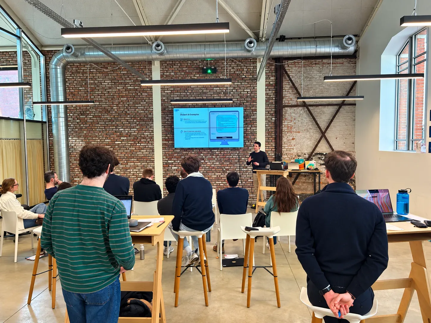 Maxime Dedeyne geeft een ArrowEye-sessie voor een groep in een loft en licht een slide met voorbeelden toe
